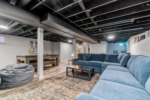 Contemporary basement living room with blue sofa and game table.