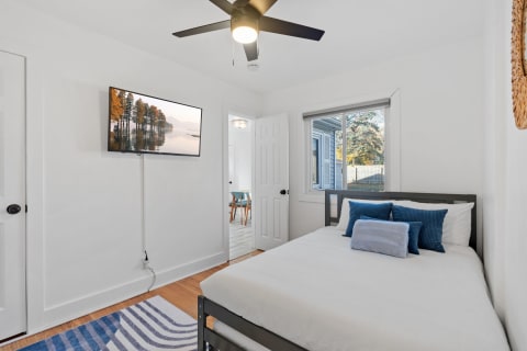 Cozy bedroom with a bed, TV, and window showing greenery outside.
