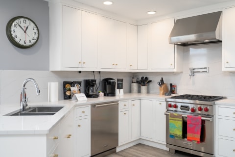 Modern kitchen featuring white cabinets, stainless steel appliances, and colorful dish towels.