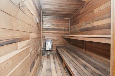A cozy wooden sauna featuring benches and a heater.
