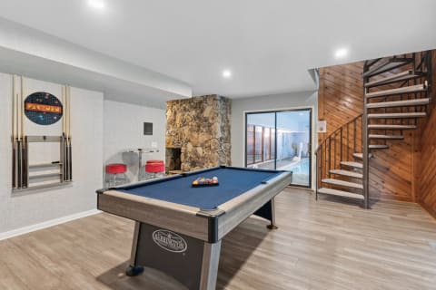 Cozy game room with billiard table and sliding doors to an indoor pool.