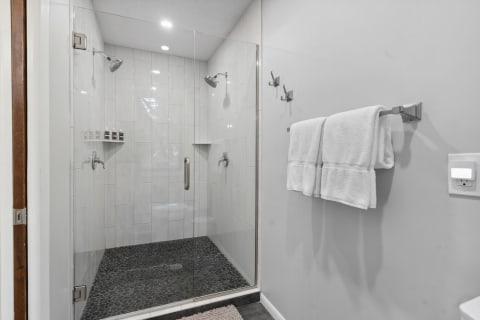 Modern bathroom with walk-in shower and pebble stone flooring.