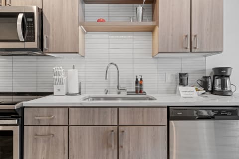 A modern kitchen with a white marble countertop, stainless steel appliances, and wooden cabinets.
