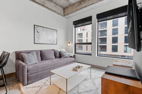 Modern living room featuring a grey couch, a white coffee table, and large windows.