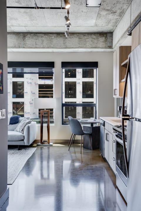 Interior view of a modern apartment showcasing kitchen and living area with concrete flooring and stylish decor.