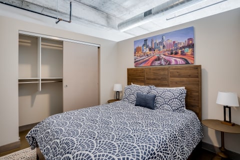 Cozy bedroom with a patterned bedspread, city skyline artwork, and sliding closet.