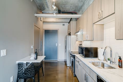 Modern kitchen in an apartment with light wood cabinets and a small dining table setup.