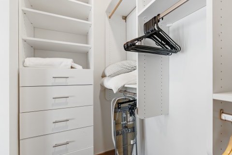 Interior view of a neatly organized closet featuring shelves, drawers, and hangers.