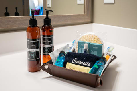 Bathroom countertop with lotion and hand soap bottles next to a container of grooming items.