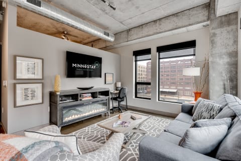 A contemporary living room featuring a gray couch, modern decor, and large windows with a view.