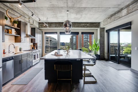 Modern kitchen with large island, dark cabinetry, and city views through windows.