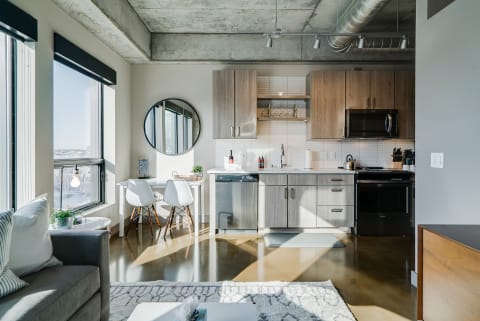Contemporary kitchen and dining space with natural light, wood cabinets, and a cozy couch.