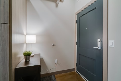 A clean and modern entryway with a console table, lamp, and navy blue door.