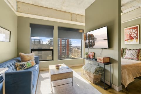 Stylish living area featuring a blue couch, a coffee table, and a view of the city through large windows.