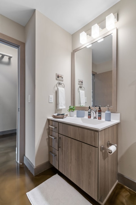 Modern bathroom with wooden vanity and lighted mirror.
