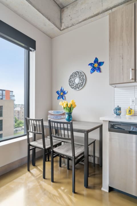 Cozy dining nook with table, chairs, decorative flowers on the wall, and a vase of tulips.