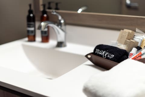 Modern bathroom sink with grooming products and a makeup towel.