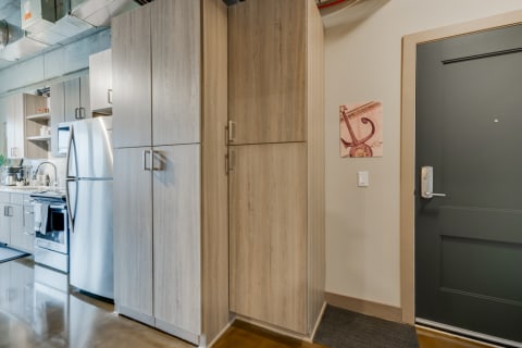 Interior view of a contemporary kitchen area with light cabinetry and a dark green door.