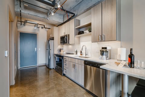 A modern kitchen with light wood cabinetry and stainless steel appliances.