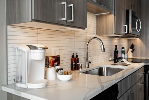 A contemporary kitchen featuring a white countertop, coffee maker, and polished faucet.