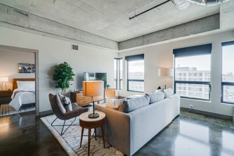 Contemporary living room featuring a gray sofa, geometric armchair, and panoramic city view through large windows.