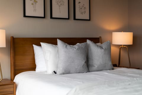 Cozy bedroom featuring a wooden bed, decorative pillows, and framed artwork.