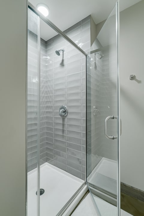 Contemporary shower with glass doors and gray tile walls.