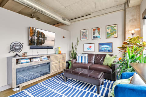 Modern living room featuring a leather sofa, a television, and colorful decor.