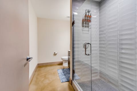 Interior view of a modern bathroom with a glass shower and a white toilet.