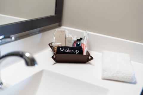 Organized bathroom countertop with makeup items in a dark brown tray and a white washcloth.