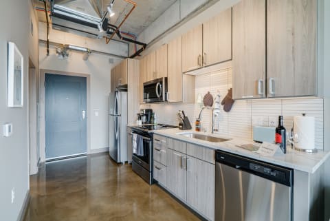 Modern kitchen with light wood cabinets and stainless steel appliances.