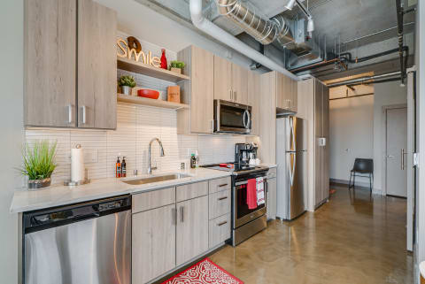 Contemporary kitchen with light wood cabinets, stainless appliances, and cheerful decorations.