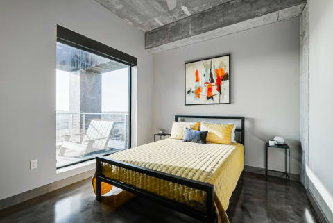 Modern bedroom with yellow quilted bedspread and abstract artwork.