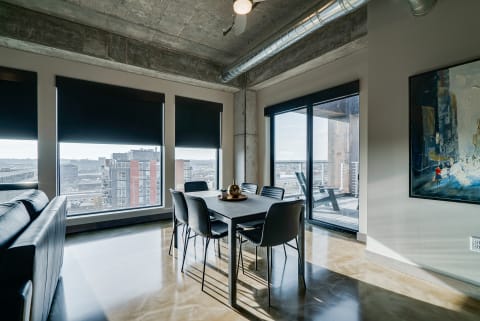 A stylish dining area featuring a black table and chairs, large windows with city views, and modern decor details.