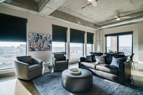 Stylish modern living room featuring leather sofa, gray armchairs, and city skyline art.