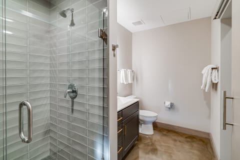 Contemporary bathroom with a glass shower, dark vanity, and white towels.