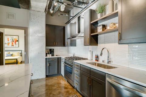 Modern kitchen with dark cabinets, stainless steel appliances, and polished concrete floor.