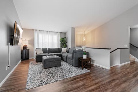 A modern living room featuring a gray sectional couch, wooden flooring, and elegant decor.
