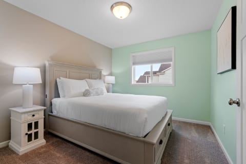 Cozy bedroom with a queen-sized bed, bedside lamps, and art on the walls.