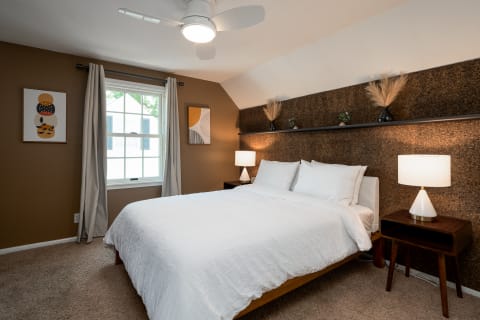 A cozy bedroom with a bed, cork wall, and minimalist decor.