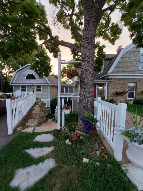 Inviting pathway and gardens leading to a charming home with decorative flower arrangements.