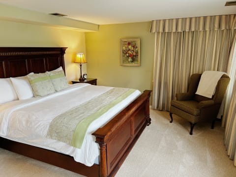 A well-furnished bedroom featuring a wooden bed, soft linens, and a reading chair by the window.