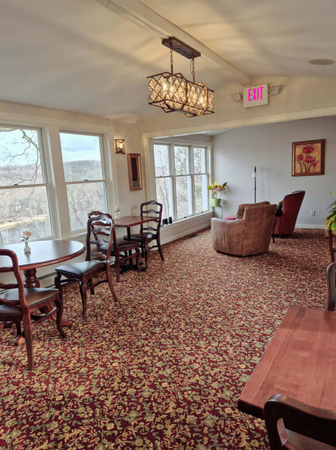 A bright communal space with large windows, wooden furniture, and decorative elements, creating a warm atmosphere.