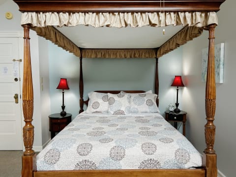 Elegant four-poster bed with intricate wood carvings and soft linens in a cozy bedroom setting.