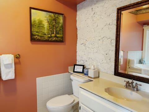 Cozy bathroom featuring peach walls, a decorative painting, and rustic white accents.