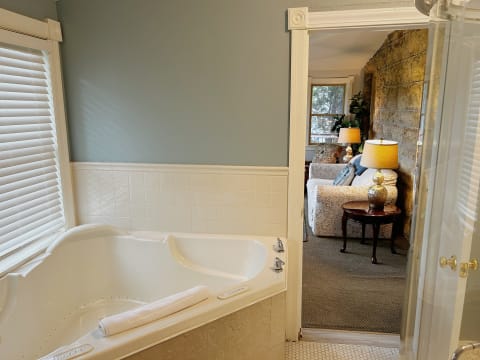 A jetted tub in a serene bathroom with a view into a cozy living space.