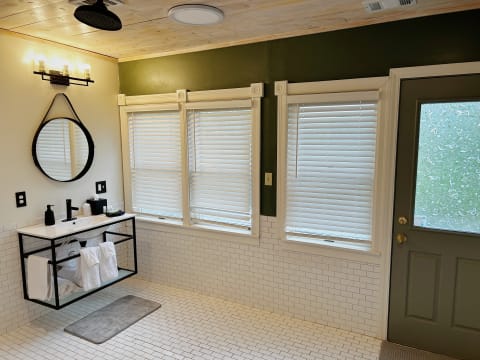 A bright modern bathroom with a floating vanity and multiple windows.