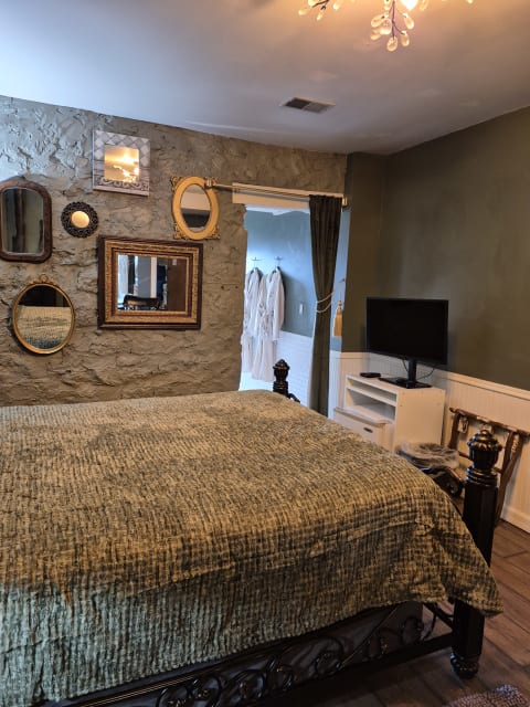 Cozy bedroom with king bed, textured coverlet, mirrors on the wall, and soft lighting.