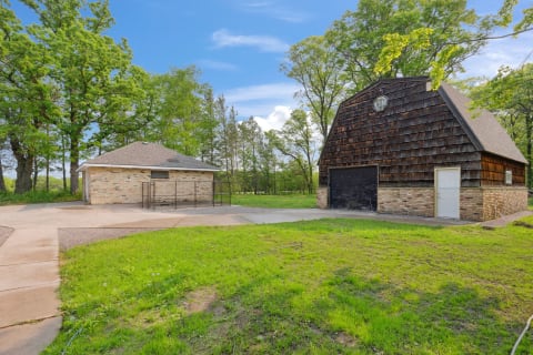 Brick garage and wooden barn in a lush green landscape.