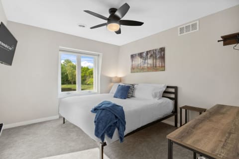 Cozy bedroom with modern furnishings and a view of greenery from the window.